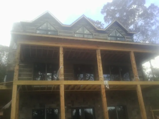 Dormers and porch framing on a large log home under construction — Roof Coating work by our crew in Aurora